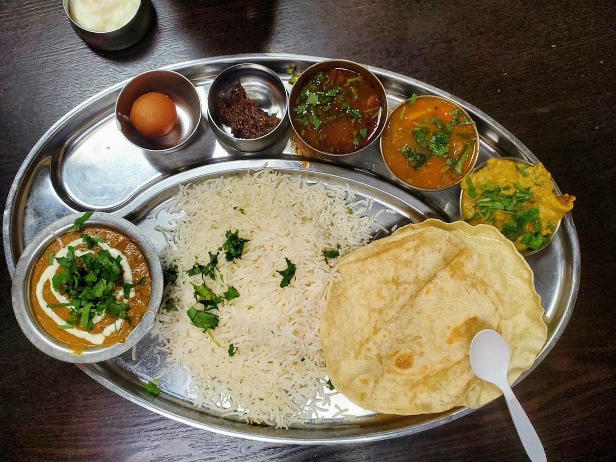 Mittagessen mit Reis, Dal und Fladenbrot auf einem Metallteller